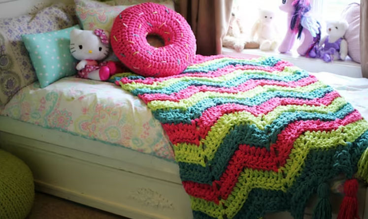 Colored crochet chevron blanket over the bed